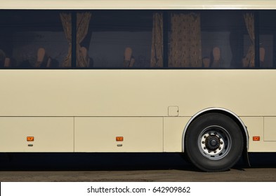 Photo Of The Hull Of A Large And Long Yellow Bus With Free Space For Advertising. Close-up Side View Of A Passenger Vehicle For Transportation And Tourism