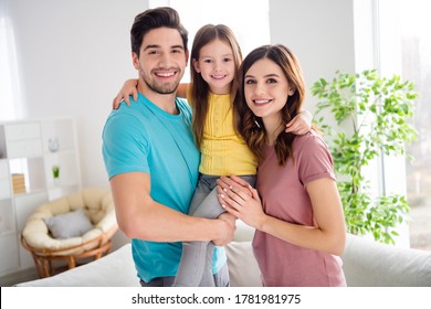 Photo of idyllic three people mommy daddy carry small kid daughter enjoy gentle bonding emotions hug embrace in house indoors