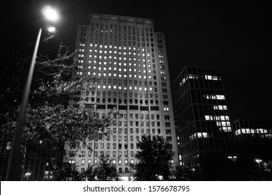 Photo illustrates a black and white building exposure taken at South Bank, London, UK on the 22nd November 2019. Photo shows commercial building from a distance and a park light.