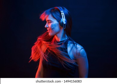 Photo im motion. Studio shot in dark studio with neon light. Portrait of young girl. - Powered by Shutterstock