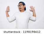 Photo image of young funny Asian man afraid expression with hands raised up, surrender, while standing over white background