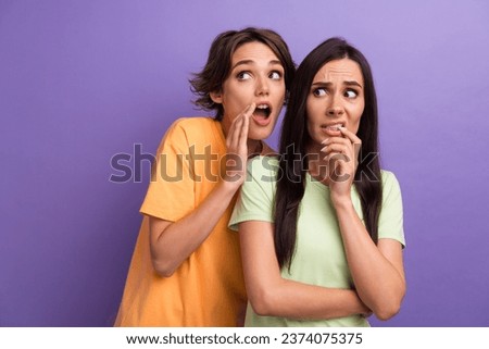 Photo of impressed confused ladies wear t-shirts arm mouth listening secrets empty space isolated violet color background
