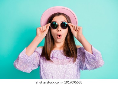 Photo of impressed cute brunette girl wear spectacles purple shirt cap isolated on blue color background