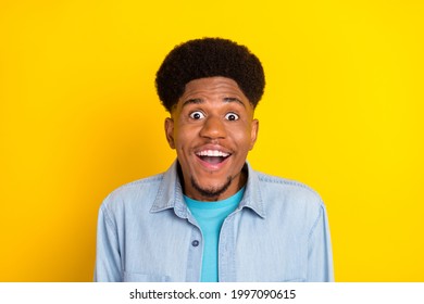 Photo of impressed funky dark skin guy dressed denim shirt smiling open mouth big eyes isolated yellow color background