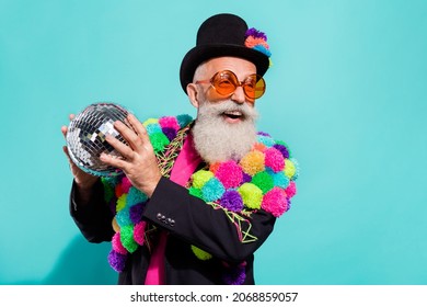 Photo of impressed funky senior hipster wear diy pop-pom blazer holding disco ball empty space smiling isolated teal color background