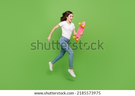 Photo of impressed funky young lady wear white t-shirt jumping running riding long board isolated green color background Stock photo © 