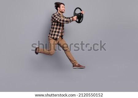 Photo of impressed funny man wear plaid shirt jumping high driving car isolated grey color background