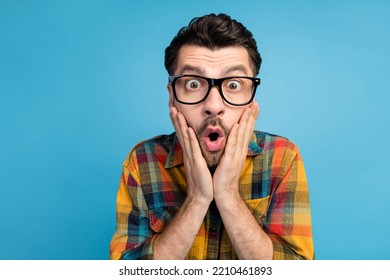 Photo Of Impressed Handsome Man In Eyeglasses Staring At Unbelievable Sale Hands Cheekbones Open Mouth Isolated On Blue Color Background