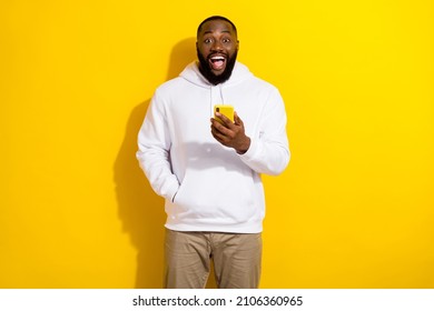 Photo Of Impressed Millennial Beard Man Hold Telephone Wear White Sportscloth Isolated On Yellow Color Background