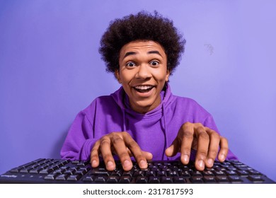 Photo of impressed overjoyed guy afro hairdo dressed purple pullover chatting on computer keyboard isolated on violet color background - Shutterstock ID 2317817593