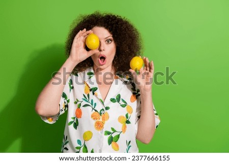 Photo of impressed pretty girl open mouth hands hold lemon cover one eye empty space isolated on green color background