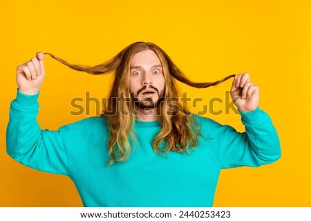 Photo of impressed speechless man hands hold hair ends staring unbelievable isolated on yellow color background