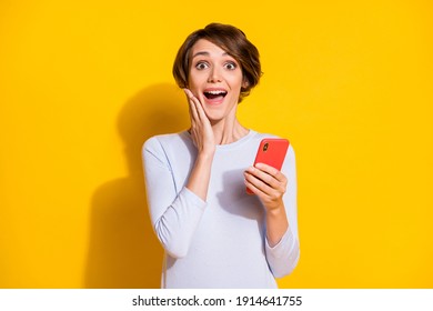Photo of impressed sweet young lady dressed white shirt arm cheek holding modern gadget isolated yellow color background