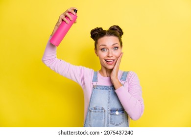 Photo Of Impressed Sweet Young Lady Dressed Jeans Overall Arm Cheek Applying Hairspray Isolated Yellow Color Background