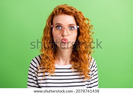 Photo of impressed sweet young woman wear striped shirt spectacles sending you kiss isolated green color background