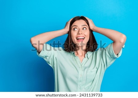 Photo of impressed woman with bob hairstyle dressed teal shirt staring at sale empty space arms on head isolated on blue color background