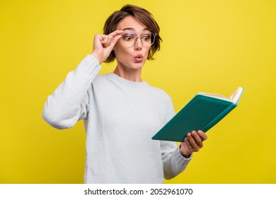 Photo of impressed young brunette lady read book wear eyeweear blue sweater isolated on yellow color background - Shutterstock ID 2052961070
