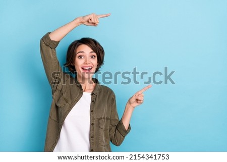 Photo of impressed young brunette lady indicate promotion wear shirt isolated on blue color background
