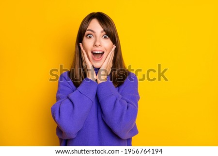 Photo of impressed young girl hands on cheeks open mouth staring camera isolated on yellow color background