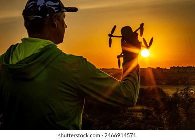 The photo includes: man, drone, sunset, silhouette, cap, cityscape, nature, evening, light, horizon. - Powered by Shutterstock