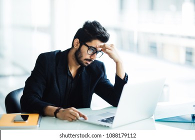 Photo of an Indian male frustrated with work sitting in front of a laptop.