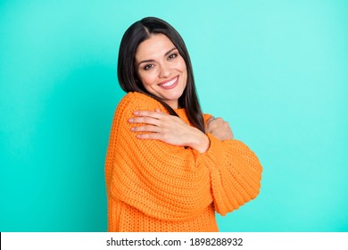 Photo of inspired tender woman embrace herself wear orange sweater isolated turquoise color background