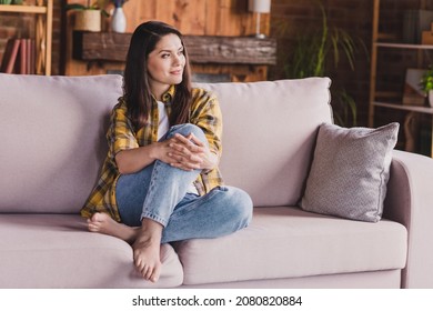 Photo of interested lovely lady look side think thoughts barefoot sit sofa wear checkered shirt home indoors