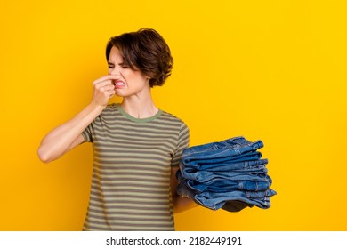 Photo of irritated displeased girl dressed green t-shirt disgusting dirty clothes aroma close nose isolated yellow color background - Shutterstock ID 2182449191