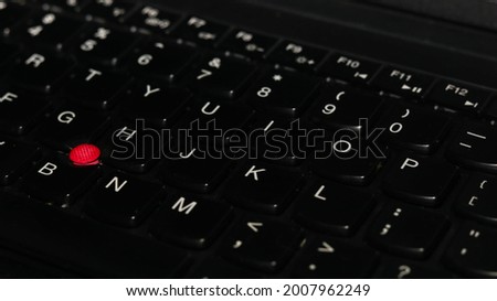 photo of keyboard with red trackpoint pointer, selective focus

