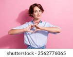 Photo of kind lovely positive woman with accessories on neck dressed blue shirt showing heart symbol isolated on pink color background