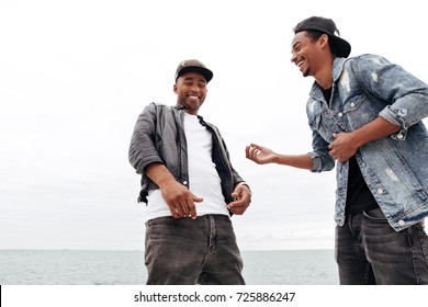 Photo Of Laughing Two Young African Men Friends Walking Outdoors Talking With Each Other.