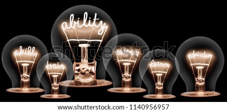 Photo of light bulb group with shining fibers in ABILITY, SKILL, TRAIN, TALENT, LEARN and EDUCATION shape isolated on black background