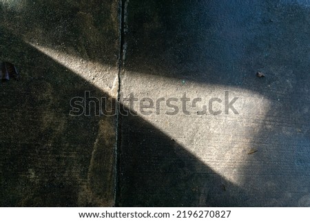Photo of light coming through the roof onto the cement floor, shadows and reflections