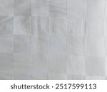 A photo of light-colored grid pattern of a clean white blanket inside a hotel room. The blanket