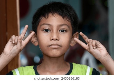 Photo of little boy show V-sign. Young boy giving peace sign.