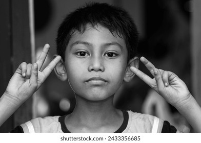 Photo of little boy show V-sign. Young boy giving peace sign. black and white photo.
