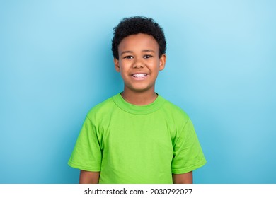 Photo of little brunet boy wear green t-shirt isolated on blue color background