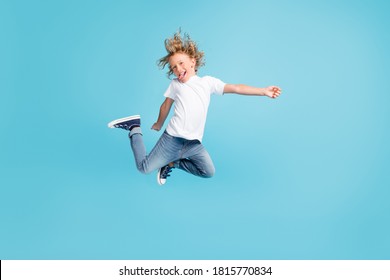 Photo of little child jump raise legs stick-out tongue wear white shirt jeans sneakers isolated blue color background - Powered by Shutterstock