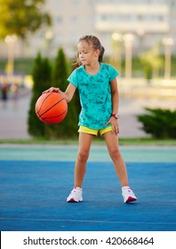 photo of little cute girl playing basketball outdoors