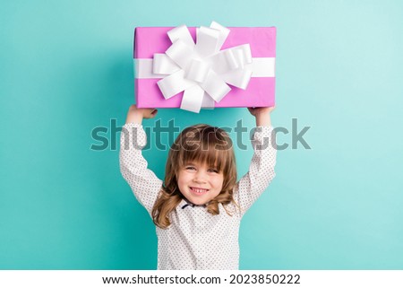 Photo of little funny girl hold present wear white shirt isolated on blue color background