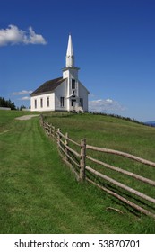 Photo of a little white wooden church in the countryside.