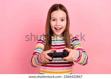 Photo of little young girl brown hair playing wireless gamepad surprised kid addiction fortnite isolated on pastel pink color background