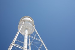 Photo Looking Up At A White Water Tower With A Bright Blue Sky.  