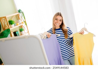 Photo of lovely blonde young girl hold dress hanger prepare date dressed striped garment spacious house indoors room - Powered by Shutterstock