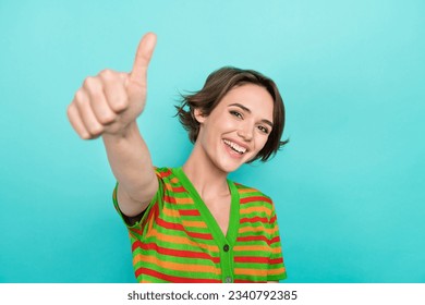 Photo of lovely cheerful girl beaming smile hand finger demonstrate thumb up isolated on teal color background - Powered by Shutterstock