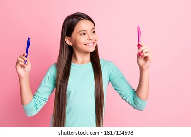 Photo of lovely cute small clever latin lady long hairstyle hands hold two pen look best choice option profitable proposition wear turquoise sweatshirt isolated pink color background - Powered by Shutterstock