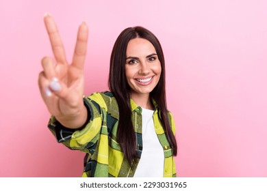 Photo of lovely positive person toothy smile arm fingers demonstrate v-sign isolated on pink color background