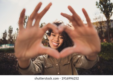 Photo of lovely wavy hairdo dark skin girlfriend show fingers heart symbol beaming smile good vibes weekend outdoors