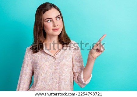 Photo of lovely young woman look curious finger point empty space dressed stylish smart casual look isolated on aquamarine color background