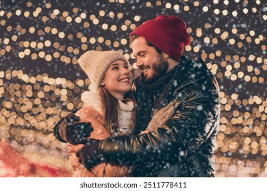 Photo of loving couple embrace under x-mas evening outdoors lights wear season winter coats headwear - Powered by Shutterstock